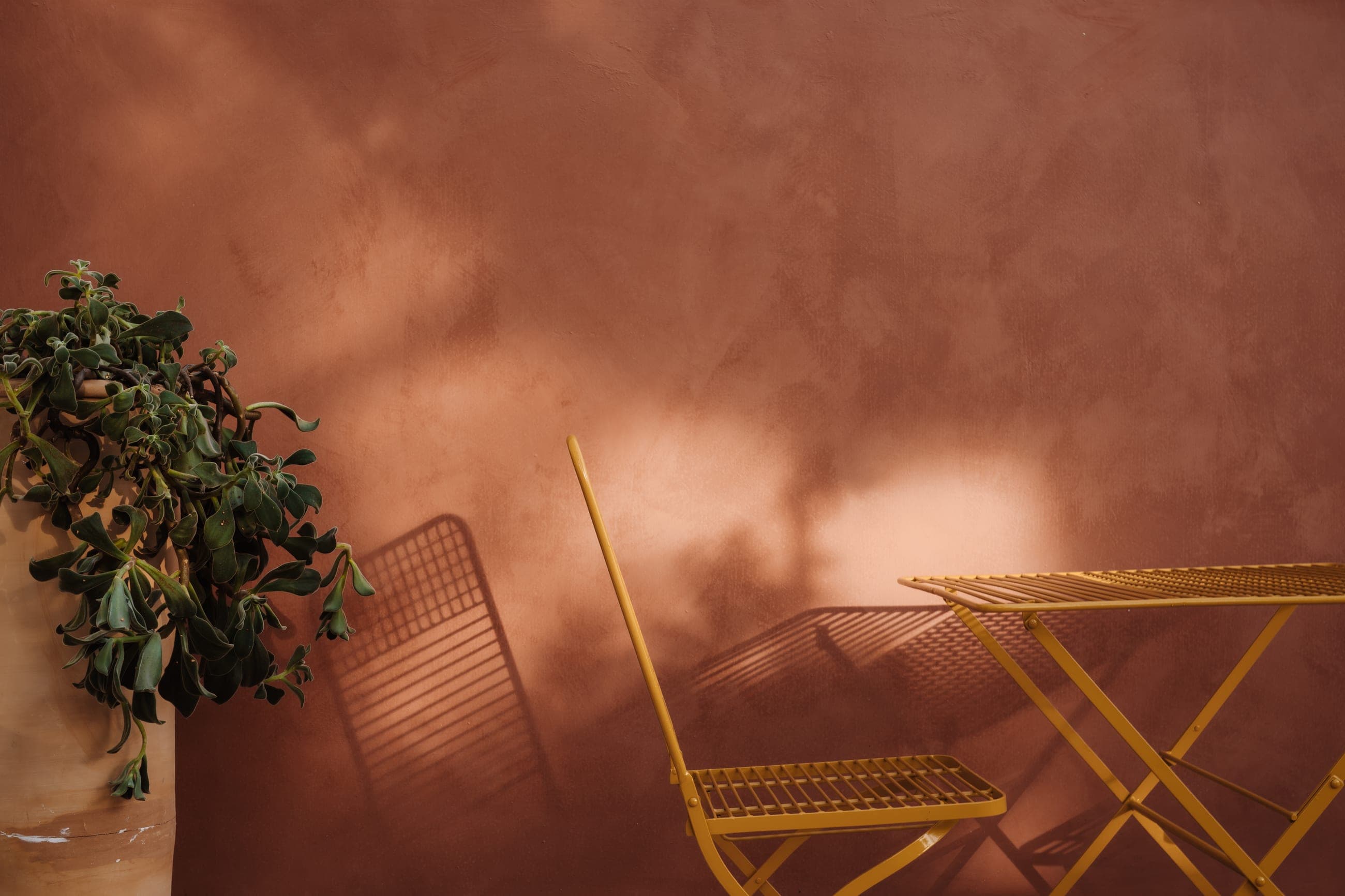 Stanza Due - Sedia gialla di profilo sul muro rosso terracotta